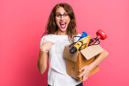 Foto de Hispanic pretty woman feeling happy and pointing to self with an excited with a tool box. handyman concept - Imagen libre de derechos