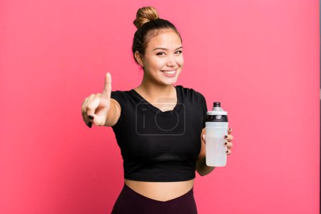 Téléchargez les photos : Hispanic pretty woman smiling proudly and confidently making number one. gym and fitness concept - en image libre de droit