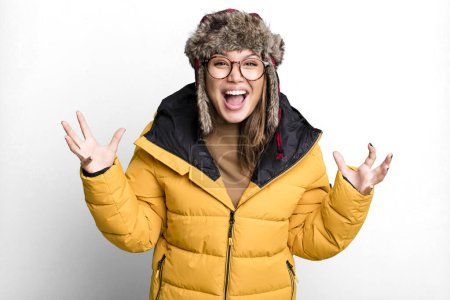 Foto de Hispanic pretty woman feeling happy and astonished at something unbelievable wearing anorak. cold and winter concept - Imagen libre de derechos