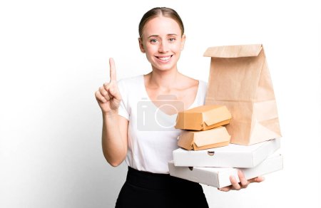 Foto de Caucasian pretty woman smiling and looking friendly, showing number one. with fast food packages. delivery concept - Imagen libre de derechos