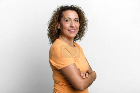 Photo for Middle age hispanic woman smiling to camera with crossed arms and a happy, confident, satisfied expression, lateral view - Royalty Free Image