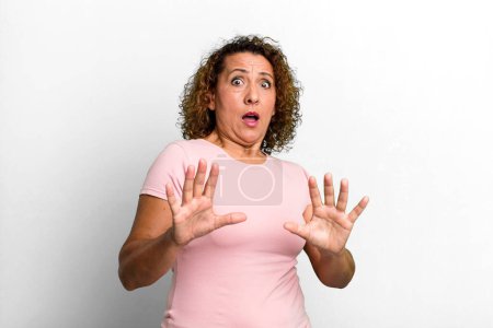Photo for Middle age hispanic woman feeling terrified, backing off and screaming in horror and panic, reacting to a nightmare - Royalty Free Image
