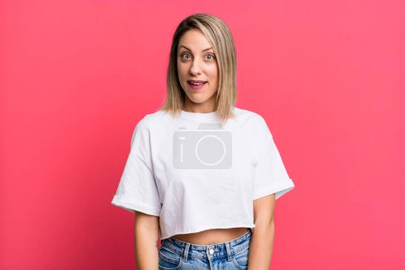 Photo for Blonde adult woman looking happy and pleasantly surprised, excited with a fascinated and shocked expression - Royalty Free Image
