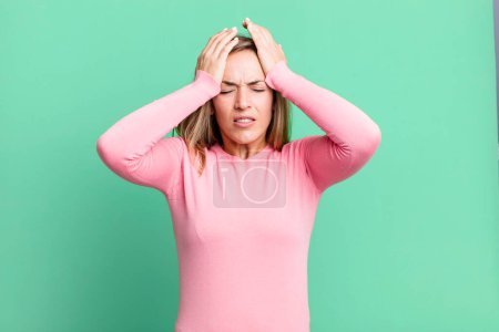 Photo for Blonde adult woman feeling stressed and anxious, depressed and frustrated with a headache, raising both hands to head - Royalty Free Image