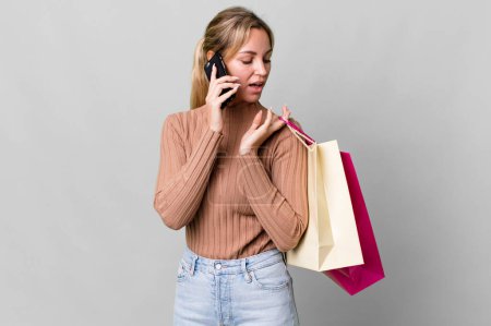 Téléchargez les photos : Pretty caucasian woman with shopping bags and a smartphone - en image libre de droit
