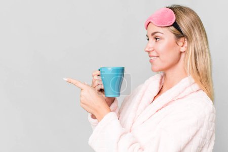 Téléchargez les photos : Pretty caucasian woman wearing night wear and having a coffee cup for breakfast - en image libre de droit