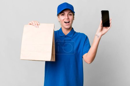 Téléchargez les photos : Pretty caucasian  delivery woman with a paper bag and a phone - en image libre de droit