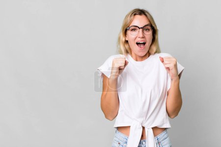 Téléchargez les photos : Caucasian blonde woman feeling shocked,laughing and celebrating success. copy space concept - en image libre de droit