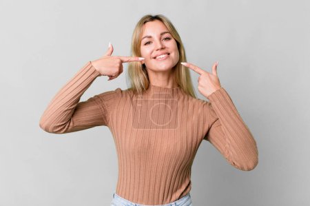 Téléchargez les photos : Caucasian blonde woman smiling confidently pointing to own broad smile - en image libre de droit