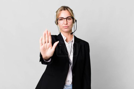 Photo for Caucasian blonde woman looking serious showing open palm making stop gesture. telemarketing cocnept - Royalty Free Image
