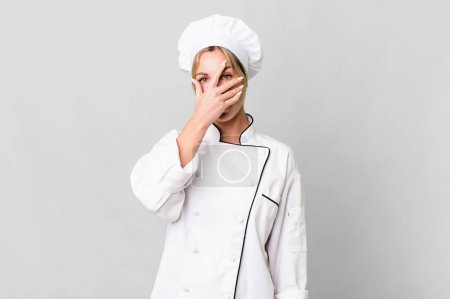 Photo for Caucasian blonde woman looking shocked, scared or terrified, covering face with hand. chef concept - Royalty Free Image