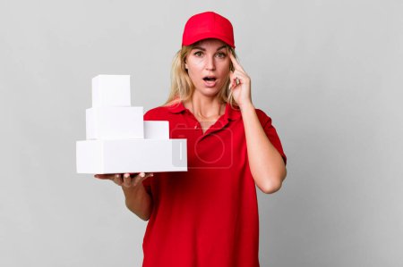 Photo for Caucasian blonde woman looking surprised, realizing a new thought, idea or concept. delivery boxes - Royalty Free Image