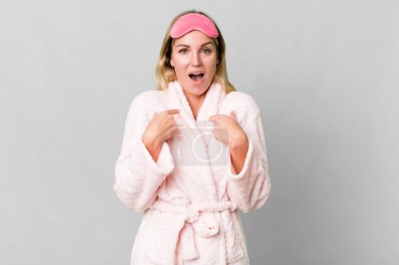 Foto de Caucasian blonde woman feeling happy and pointing to self with an excited. night wear concept - Imagen libre de derechos