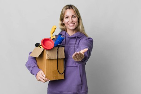 Foto de Caucasian blonde woman smiling happily with friendly and  offering and showing a concept. housekeeper concept - Imagen libre de derechos