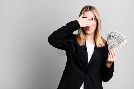 Photo for Young pretty woman looking shocked, scared or terrified, covering face with hand. business and money concept - Royalty Free Image