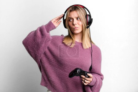 Photo for Young pretty woman smiling happily and daydreaming or doubting. gamer with headset and controller - Royalty Free Image