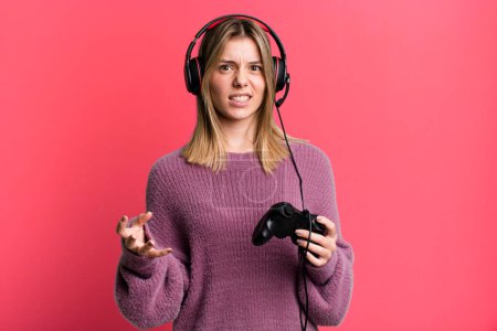 Foto de Joven bonita mujer mirando enojado, molesto y frustrado. gamer con auriculares y controlador - Imagen libre de derechos