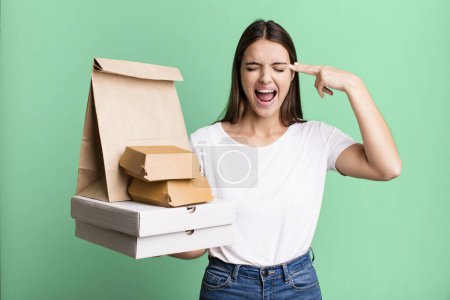 Photo for Young pretty woman looking unhappy and stressed, suicide gesture making gun sign. delivery and take away concept - Royalty Free Image