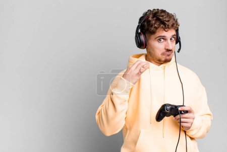 Foto de Young adult caucasian man looking arrogant, successful, positive and proud with headset and a controller. gamer concept - Imagen libre de derechos