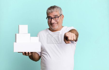 Photo for Middle age senior man pointing at camera choosing you. different packages blank boxes - Royalty Free Image