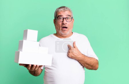 Photo for Middle age senior man looking shocked and surprised with mouth wide open, pointing to self. different packages blank boxes - Royalty Free Image
