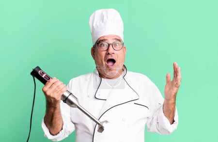 Photo for Middle age senior man feeling extremely shocked and surprised. restaurant chef with a tool concept - Royalty Free Image