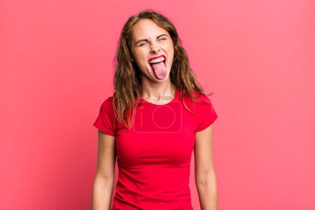 Foto de Joven bonita mujer con actitud alegre, despreocupada, rebelde, bromeando y sacando la lengua, divirtiéndose - Imagen libre de derechos