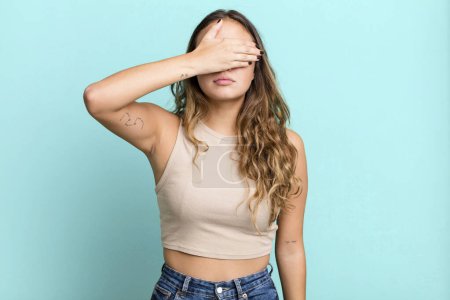Photo for Young pretty woman covering eyes with one hand feeling scared or anxious, wondering or blindly waiting for a surprise - Royalty Free Image