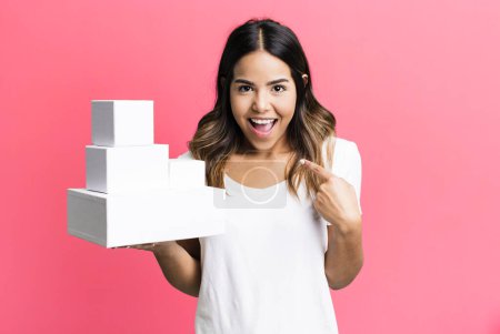 Photo for Hispanic pretty woman feeling happy and pointing to self with an excited with blank packages boxes - Royalty Free Image