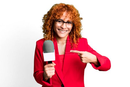 Téléchargez les photos : Red hair pretty woman smiling cheerfully, feeling happy and pointing to the side. journalist and presenter concept - en image libre de droit