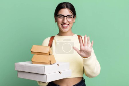 Foto de Smiling and looking friendly, showing number five. fast food delivery or take away - Imagen libre de derechos