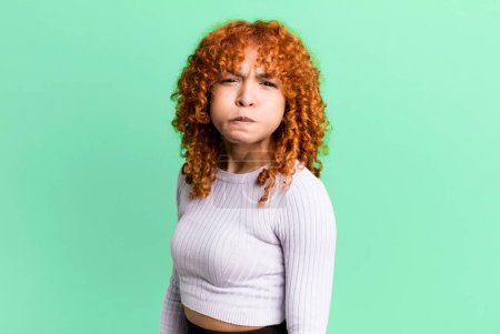 Photo for Redhair pretty woman with a goofy, crazy, surprised expression, puffing cheeks, feeling stuffed, fat and full of food - Royalty Free Image
