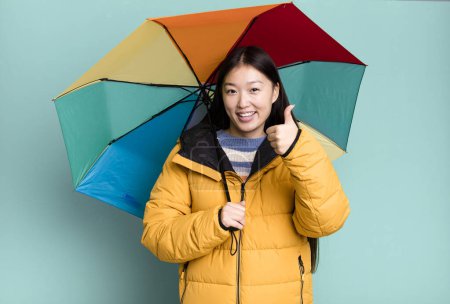 Photo for Young adult pretty asian woman wearing anorak and an umbrella. winter and cold concept - Royalty Free Image