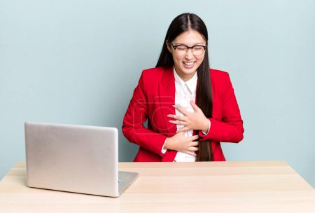 Téléchargez les photos : Pretty asian woman laughing out loud at some hilarious joke. business desk concept - en image libre de droit