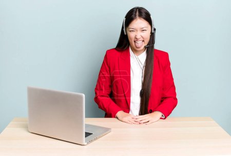 Photo for Pretty asian woman with cheerful and rebellious attitude, joking and sticking tongue out. business desk concept - Royalty Free Image