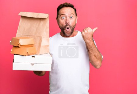 Photo for Middle age man looking astonished in disbelief. delivery and fast food take away concept - Royalty Free Image