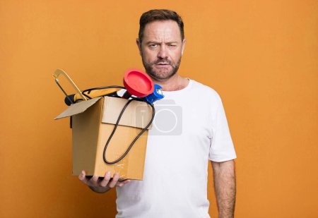 Foto de Middle age man feeling puzzled and confused. handyman with a toolbox - Imagen libre de derechos