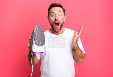 Photo for Middle age man amazed, shocked and astonished with an unbelievable surprise. housekeeper concept - Royalty Free Image