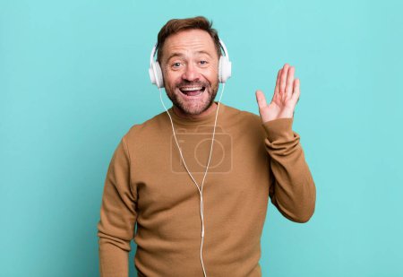 Foto de Middle age man feeling happy, surprised realizing a solution or idea. listening music with a headphones - Imagen libre de derechos