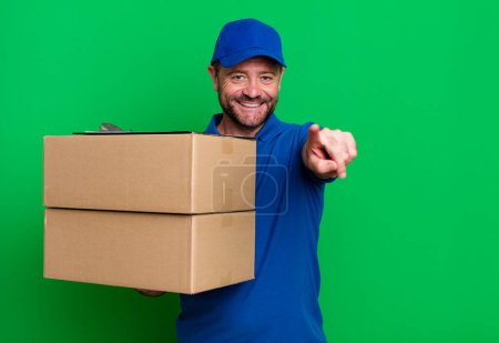 Téléchargez les photos : Middle age man pointing at camera choosing you. paker delivery man. packer delivery man - en image libre de droit