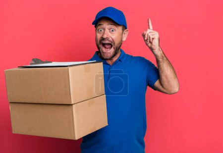 Téléchargez les photos : Middle age man feeling like a happy and excited genius after realizing an idea. paker delivery man. packer delivery man - en image libre de droit