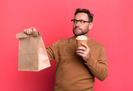 Foto de Hombre de mediana edad con un café para llevar concepto entrenador deportivo con una pelota de fútbol - Imagen libre de derechos