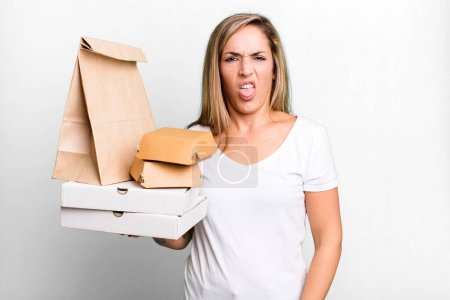 Téléchargez les photos : Pretty blonde woman feeling disgusted and irritated and tongue out. delivery take away food packages concept - en image libre de droit