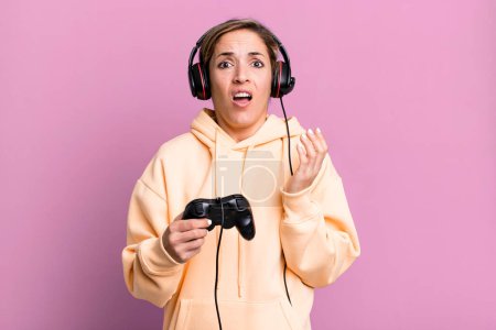 Téléchargez les photos : Pretty blonde woman looking desperate, frustrated and stressed. gamer with headset and a controller - en image libre de droit