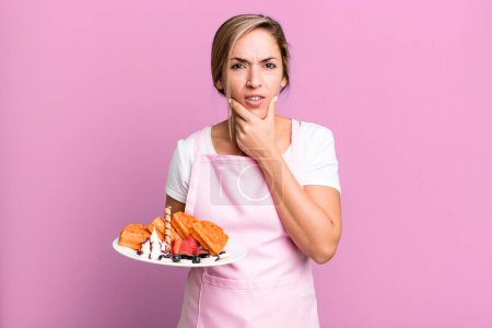 Foto de Pretty blonde woman with mouth and eyes wide open and hand on chin. home made waffles concept - Imagen libre de derechos