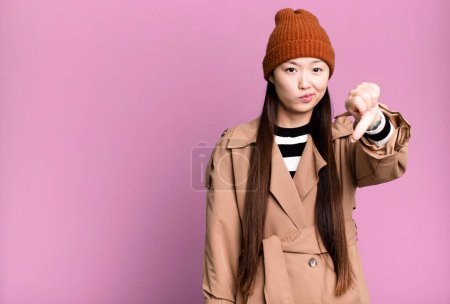 Photo for Pretty asian woman feeling cross,showing thumbs down - Royalty Free Image
