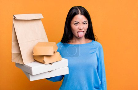 Photo for Hispanic pretty woman feeling disgusted and irritated and tongue out. with take away fast food packages - Royalty Free Image