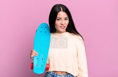 Photo for Hispanic pretty woman looking puzzled and confused. skate boarding concept - Royalty Free Image