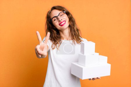 Photo for Hispanic pretty woman smiling and looking friendly, showing number two. with white boxes packages - Royalty Free Image