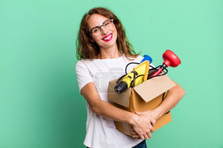 Photo for Hispanic pretty woman smiling happily with a hand on hip and confident with a tool box. handyman concept - Royalty Free Image